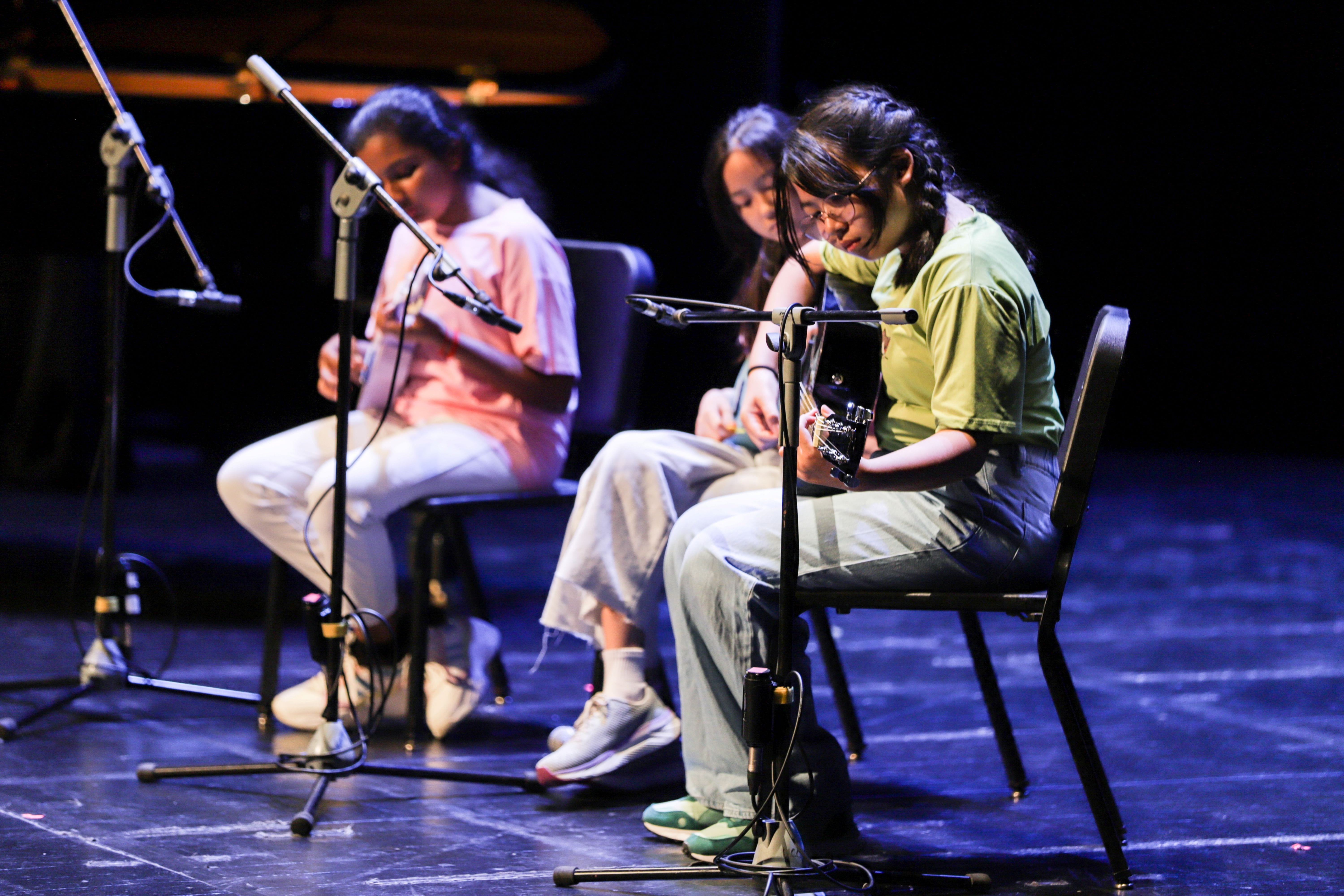 Photo of 3 students playing guitar on stage.